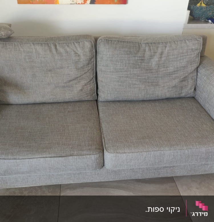 ספה אפורה עם כריות על רצפת אריחים